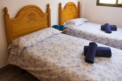 two beds in a bedroom with two blue pillows on them at APARTAMENTO LOS NARCISOS in Chulilla