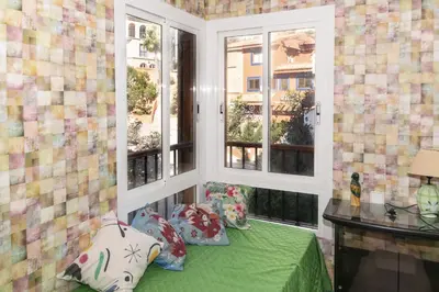 a room with two windows and a green bed with pillows at Nueva Vista 2º-4 in Cullera