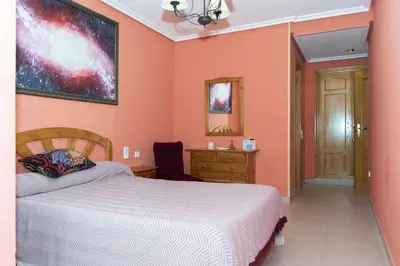a bedroom with orange walls and a bed and a dresser at Nueva Vista 2º-4 in Cullera