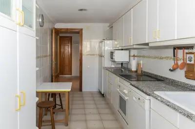 a kitchen with white cabinets and a sink and a table at Nueva Vista 2º-4 in Cullera