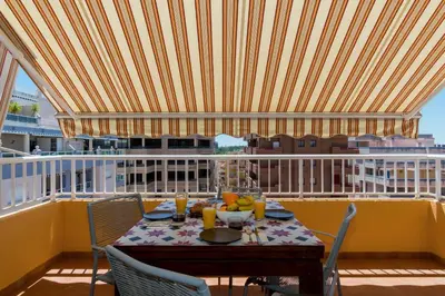 a table on a balcony with a view of a ship at Duplex Penthouse with terrace. Beach-Pool in Canet de Berenguer