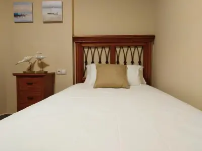a bedroom with a large white bed with a wooden headboard at PATACONA MARE NOSTRUM APARTMENT II in Valencia