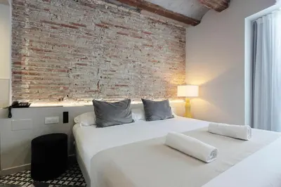 a bedroom with a large white bed with a brick wall at YOU & CO. Quart Boutique in Valencia