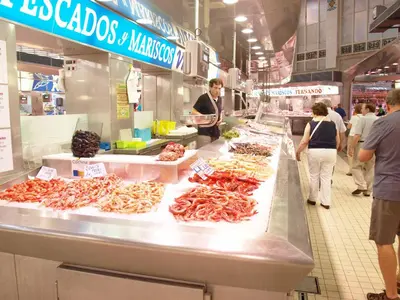 a market with people standing around a counter with seafood at ApartUP Central Market I in Valencia
