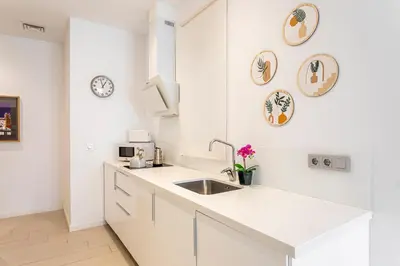 a white kitchen with a sink and clocks on the wall at R&C APARTMENTS CLOSE to CENTER in Valencia
