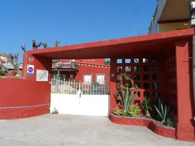 a red building with a gate and a white fence at Apartamento con terraza y vistas al mar in Burriana