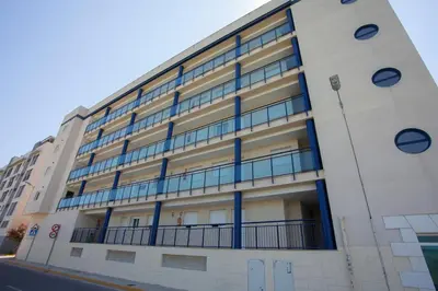 a white building with blue windows on a street at SingularStays Moncofar Beach in Moncófar