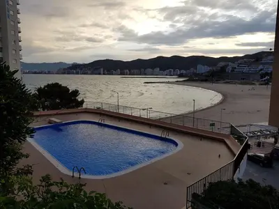 a swimming pool next to a beach and a body of water at Faro de Cullera I in Faro de Cullera