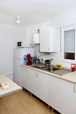 a white kitchen with a sink and a refrigerator at Calicanto House & Pool in Torrent
