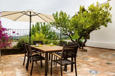 a wooden table with chairs and an umbrella on a patio at Casa rural la ermita de Anna in Anna