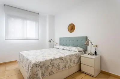 a white bedroom with a bed and a window at Playa Valencia Residencial Sol y Mar Terraza con Vistas y Parking in Playa Pobla de Farnals