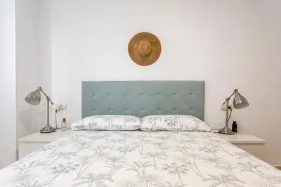 a bedroom with a bed with a blue headboard and two lamps at Playa Valencia Residencial Sol y Mar Terraza con Vistas y Parking in Playa Pobla de Farnals