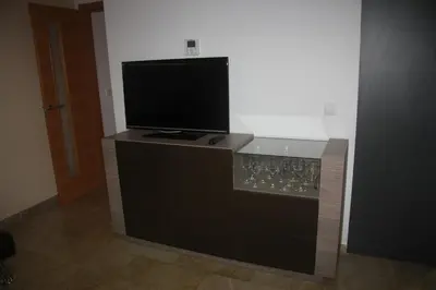 a tv on top of a bar with wine glasses at Holiday Apartments Malvarrosa Beach in Valencia