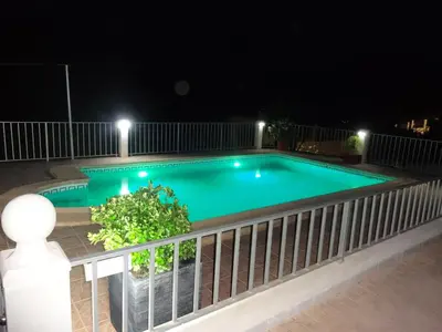 a swimming pool at night with a fence at LAS PALOMAS, appartement 3 chambres avec piscine in Turís