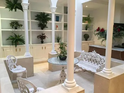 a lobby with white chairs and potted plants on shelves at Casa Modernista 