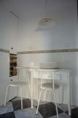 a white kitchen with a table and two stools at Bonito apartament a 3 minutos de la playa in Cullera