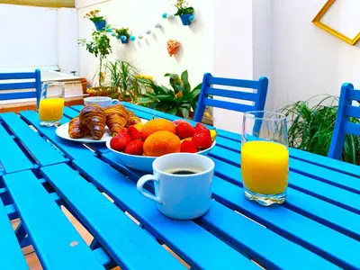a blue table with a bowl of fruit and a cup of orange juice at Emma Apartment Central in Valencia