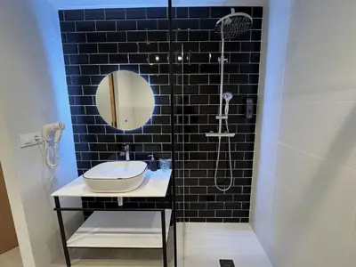 a black tiled bathroom with a sink and a shower at Hulot B&B Valencia in Valencia