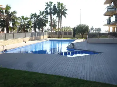 a swimming pool in a yard with palm trees at Apartamento Moncofar playa in Moncófar