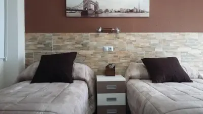 a bedroom with two beds and a brick wall at Hostal La Pilarica in Paterna