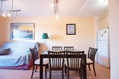 a dining room with a table and chairs and a bed at Global Vacacional, Apartamento en Marjal de Corinto con Piscina in Sagunto