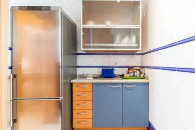 a small kitchen with blue cabinets and a refrigerator at PRECIOSO APARTAMENTO EN EL BARRIO DE RUZAFA in Valencia