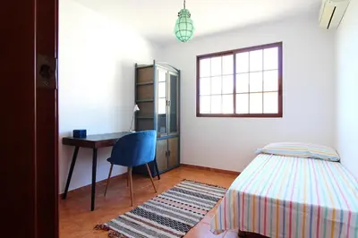 a bedroom with a bed and a desk and a window at Global Vacacional, Adosado en la playa con piscina in Sagunto