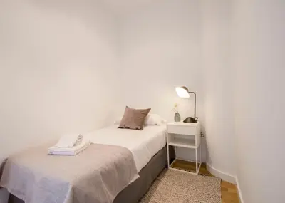 a small white bedroom with a bed and a lamp at Apartamentos San Vicente in Valencia