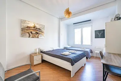 a white bedroom with a bed and a desk at Jardín Botánico Rooms in Valencia