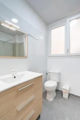a white bathroom with a toilet and a sink at Jardín Botánico Rooms in Valencia