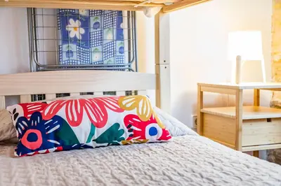 a bedroom with a bed with a colorful pillow on it at Travel Habitat Plaza de la Virgen in Valencia