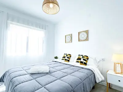 a white bedroom with a bed and a window at NUEVO, a 70 metros de la playa y con vistas al mar in Cullera