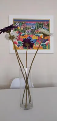 a vase with flowers on a table with a painting at Apartamento nuevo playa de Canet de Berenguer WIFI in Canet de Berenguer