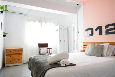 a bedroom with a large white bed with a chair at Torres de Serrano Apartment in Valencia