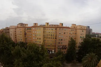 a large tan building with trees in front of it at apartemento ideal grupo y familia climatisacion y cerca playa . mongrell in Valencia