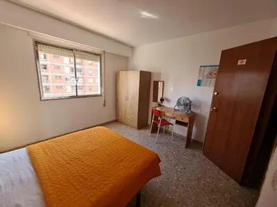 a bedroom with two beds and a desk and a window at Apartemento grupo amigo o familias : blasco ibanez C in Valencia