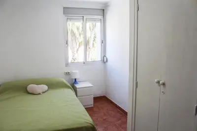a small bedroom with a green bed and a window at apartemento nuevo cerca playa para familia o amigos . isidro in Valencia