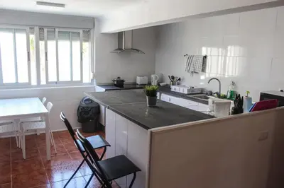 a kitchen with a counter with chairs and a table at apartemento nuevo cerca playa para familia o amigos . isidro in Valencia