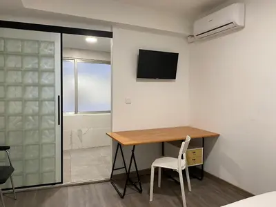 a room with a desk and a television on the wall at Shanti Rooms in Valencia