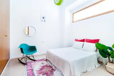 a white bedroom with a bed and a blue chair at Design, beach and city center in Valencia
