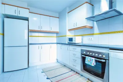 a white kitchen with white cabinets and a refrigerator at Design, beach and city center in Valencia