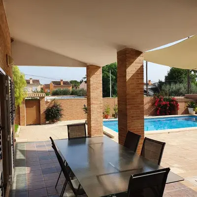 a patio with a table and chairs and a swimming pool at Maravisa in Puebla de Vallbona