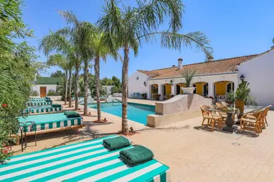 a pool with green and white benches next to a house at Maison San Alfredo B&B in El Puig