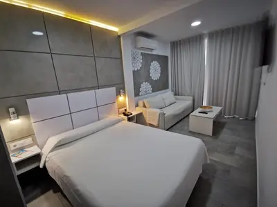 a bedroom with a large white bed and a couch at Sol Playa Suites in Valencia