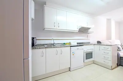 a white kitchen with white cabinets and a sink at Global Vacacional, Apartamento en la playa de Canet d'en Berenguer in Canet de Berenguer