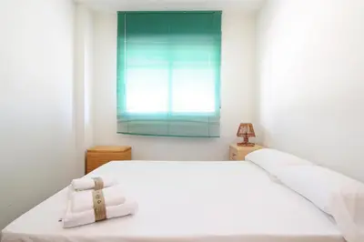 a bedroom with a white bed and a window at Global Vacacional, Estudio para parejas con piscina en Canet playa in Canet de Berenguer