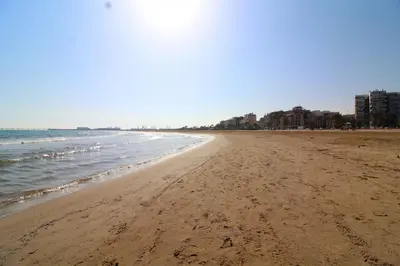 a beach with the ocean and buildings in the background at Global Vacacional, Estudio para parejas en la playa del Puerto de Sagunto in Puerto de Sagunto