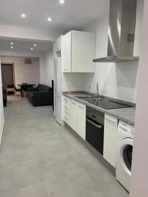 a kitchen with white appliances and a living room at UIM Mediterraneo PB Aragon B Wifi in Puerto de Sagunto