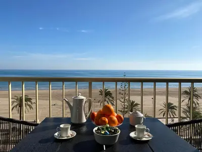 a table with a bowl of fruit on a balcony with the beach at 1a línea con PISCINA Nuevo in Cullera