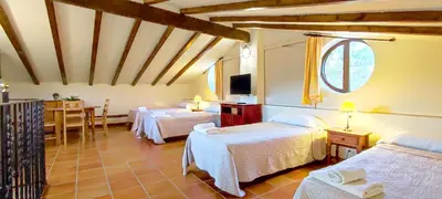 a bedroom with two beds and a table and a tv at Masía de San Juan Casas número 3 y 5, con piscina, aire acondicionado y vistas a la montaña in Segorbe